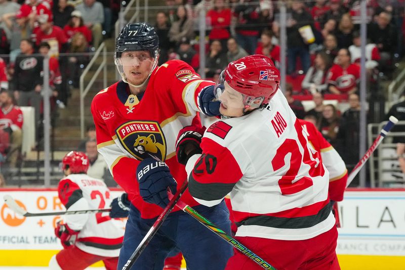 Dec 23, 2025; Raleigh, North Carolina, USA;  Florida Panthers defenseman Niko Mikkola (77) hits Carolina Hurricanes center Sebastian Aho (20) during the first period at Lenovo Center. Mandatory Credit: James Guillory-Imagn Images