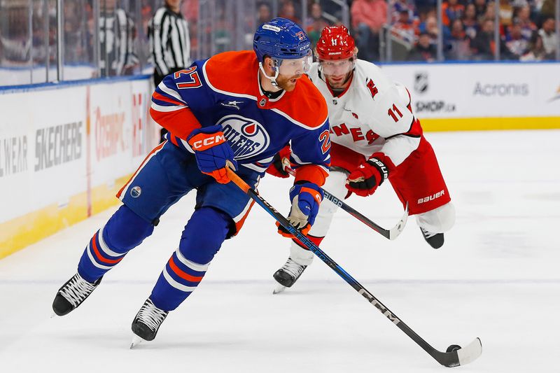 Oct 22, 2024; Edmonton, Alberta, CAN; Edmonton Oilers defensemen Brett Kulak (27) looks to move the puck in front of Carolina Hurricanes forward Jordan Staal (11) during the second period at Rogers Place. Mandatory Credit: Perry Nelson-Imagn Images