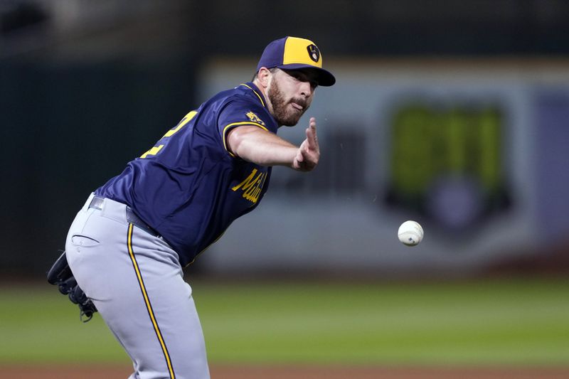 Aug 23, 2024; Oakland, California, USA; Milwaukee Brewers starting pitcher Aaron Civale (32) tosses the ball to first base to record an out against the Oakland Athletics during the fourth inning at Oakland-Alameda County Coliseum. Mandatory Credit: Darren Yamashita-USA TODAY Sports