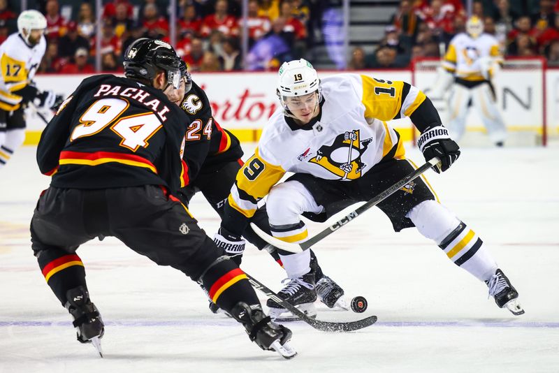 Oct 22, 2024; Calgary, Alberta, CAN; Pittsburgh Penguins center Cody Glass (19) and Calgary Flames defenseman Jake Bean (24) battles for the puck during the first period at Scotiabank Saddledome. Mandatory Credit: Sergei Belski-Imagn Images