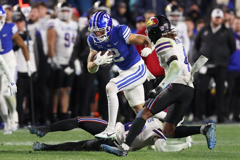 Nov 16, 2024; Provo, Utah, USA; Brigham Young Cougars wide receiver Chase Roberts (2) breaks a tackle by Kansas Jayhawks safety Taylor Davis (bottom) and safety Marvin Grant (4) defends during the fourth quarter at LaVell Edwards Stadium. Mandatory Credit: Rob Gray-Imagn Images