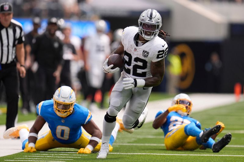 Las Vegas Raiders running back Alexander Mattison (22) runs against Los Angeles Chargers linebacker Daiyan Henley (0) and cornerback Asante Samuel Jr. during the first half of an NFL football game, Sunday, Sept. 8, 2024, in Inglewood, Calif. (AP Photo/Marcio Jose Sanchez)