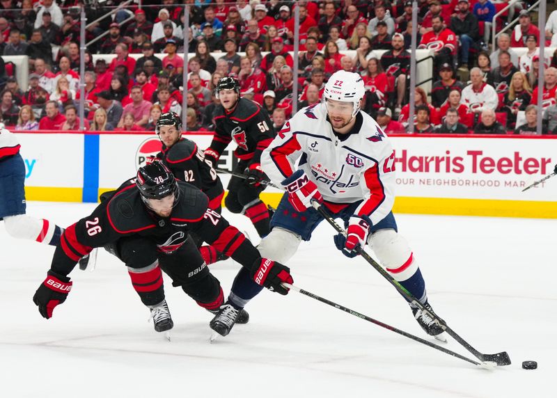 May 12, 2025; Raleigh, North Carolina, USA; Washington Capitals right wing Brandon Duhaime (22) has the puck poked away by Carolina Hurricanes defenseman Sean Walker (26) during the first period in game four of the second round of the 2025 Stanley Cup Playoffs at Lenovo Center. Mandatory Credit: James Guillory-Imagn Images