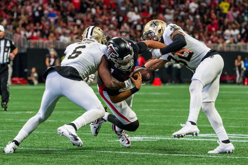 Atlanta Falcons quarterback Marcus Mariota (1) fumbles as New Orleans Saints safety Marcus Maye (6) and safety Tyrann Mathieu (32) defend during the second half of an NFL football game, Sunday, Sep. 11, 2022, in Atlanta. The New Orleans Saints won 27-26. (AP Photo/Danny Karnik)