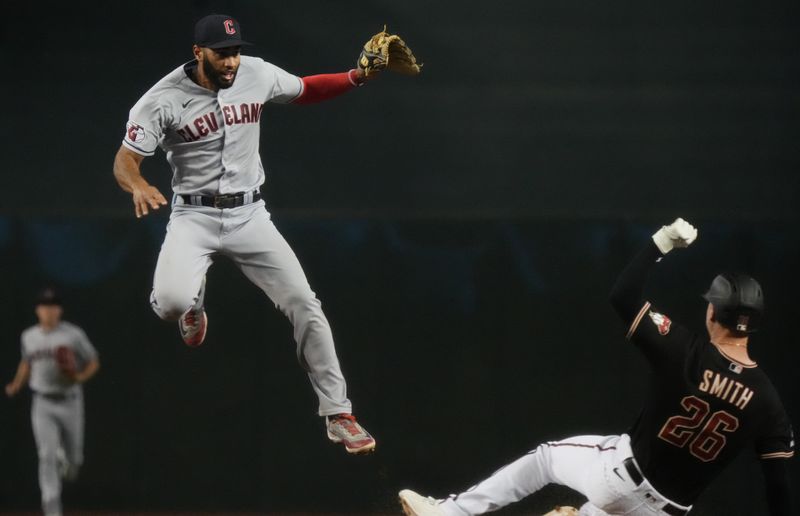 Jun 17, 2023; Phoenix, Arizona, USA; Cleveland Guardians infielder Amed Rosario (1) leaps over Arizona Diamondbacks Pavin Smith (26) while throwing to first base for the double play at Chase Field. Mandatory Credit: Joe Rondone-USA TODAY Sports