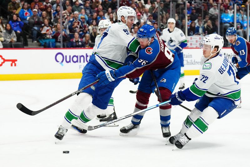 Nov 22, 2023; Denver, Colorado, USA; Vancouver Canucks defenseman Tyler Myers (57) hits Colorado Avalanche right wing Mikko Rantanen (96) as left wing Anthony Beauvillier (72) clears the puck in the second period at Ball Arena. Mandatory Credit: Ron Chenoy-USA TODAY Sports