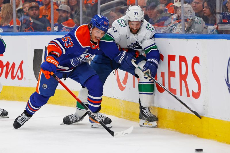 Oct 11, 2025; Edmonton, Alberta, CAN; Edmonton Oilers forward Issac Howard (53) and Vancouver Canucks defensemen Derek Forbort (27) battle along the boards for a loose puck  during the third period at Rogers Place. Mandatory Credit: Perry Nelson-Imagn Images