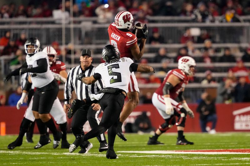 Nov 16, 2024; Madison, Wisconsin, USA;  Wisconsin Badgers wide receiver Bryson Green (9) catches a pass in front of Oregon Ducks defensive back Kobe Savage (5) during the second quarter at Camp Randall Stadium. Mandatory Credit: Jeff Hanisch-Imagn Images