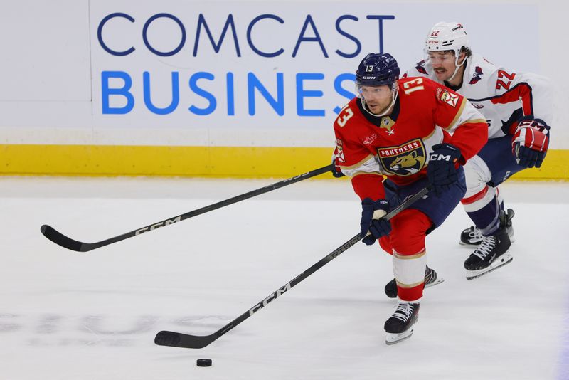 Nov 25, 2024; Sunrise, Florida, USA; Florida Panthers center Sam Reinhart (13) moves the puck ahead of Washington Capitals right wing Brandon Duhaime (22) during the third period at Amerant Bank Arena. Mandatory Credit: Sam Navarro-Imagn Images