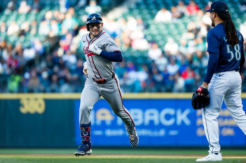 Apr 30, 2024; Seattle, Washington, USA; Atlanta Braves left fielder Jarred Kelenic (24) smiles while jogging past Seattle Mariners starting pitcher Luis Castillo (58) after hitting a fly-out during the third inning at T-Mobile Park. Mandatory Credit: Joe Nicholson-USA TODAY Sports