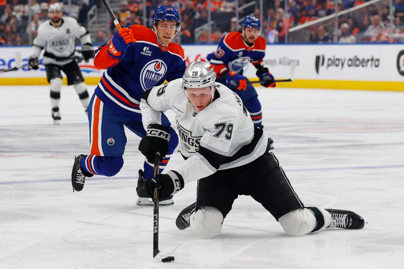 Jan 10, 2026; Edmonton, Alberta, CAN; Los Angeles Kings forward Samuel Helenius (79) tries to make a play from his knees in front of Edmonton Oilers defensemen Spencer Stastney (24) during the second period at Rogers Place. Mandatory Credit: Perry Nelson-Imagn Images