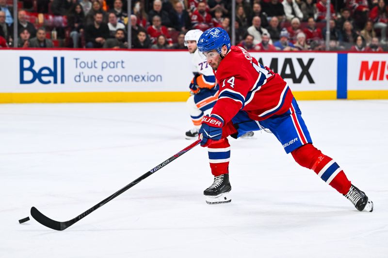 Feb 26, 2026; Montreal, Quebec, CAN; Montreal Canadiens center Nick Suzuki (14) reaches out for the puck with his stick against the New York Islanders during the second period at Bell Centre. Mandatory Credit: David Kirouac-Imagn Images