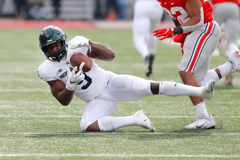 Nov 20, 2021; Columbus, Ohio, USA; Michigan State Spartans running back Kenneth Walker III (9) with the diving catch as Ohio State Buckeyes linebacker Steele Chambers (22) defends during the second quarter at Ohio Stadium. Mandatory Credit: Joseph Maiorana-USA TODAY Sports