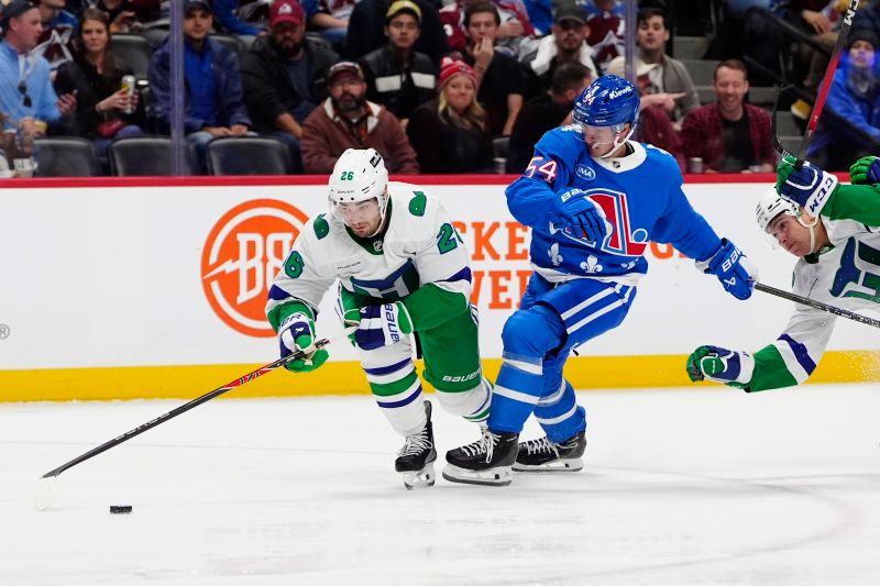 Oct 23, 2025; Denver, Colorado, USA; Carolina Hurricanes defenseman Sean Walker (26) and Colorado Avalanche center Gavin Brindley (54) during the second period at Ball Arena. Mandatory Credit: Ron Chenoy-Imagn Images