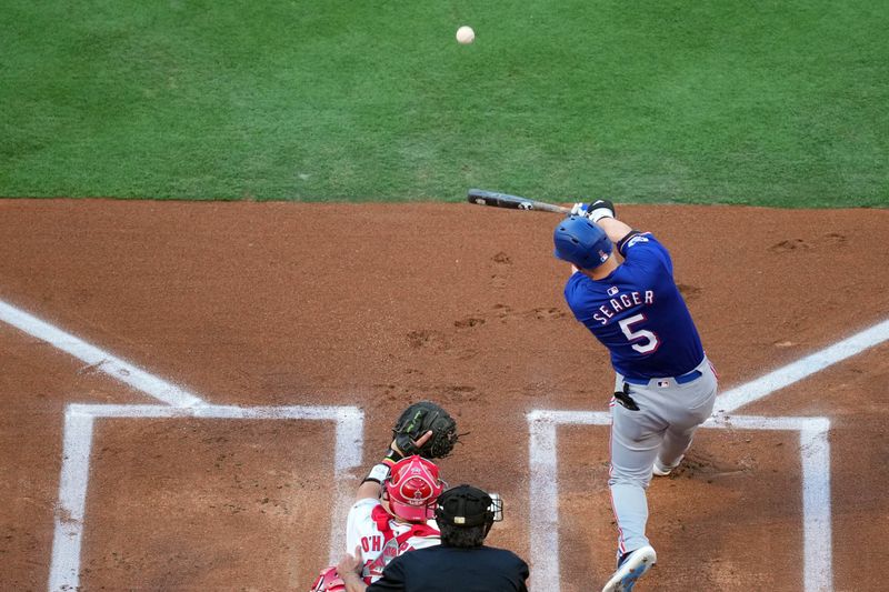 July 8, 2024; Anaheim, California, USA; Texas Rangers shortstop Corey Seager (5) hits a two-run home run in the first inning as Los Angeles Angels catcher Logan O'Hoppe (14) watches at Angel Stadium. Mandatory Credit: Kirby Lee-USA TODAY Sports