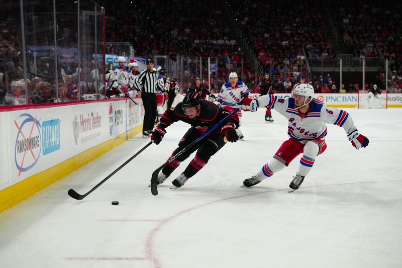 Mar 12, 2024; Raleigh, North Carolina, USA; Carolina Hurricanes defenseman Dmitry Orlov (7) skates with the puck outside of New York Rangers defenseman Zac Jones (6) during the first period at PNC Arena. Mandatory Credit: James Guillory-USA TODAY Sports