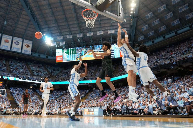 Mar 1, 2025; Chapel Hill, North Carolina, USA;  Miami (Fl) Hurricanes guard Austin Swartz (23) passes the ball as North Carolina Tar Heels forward Jae'Lyn Withers (24) and guards Seth Trimble (7) and Ian Jackson (11) defend in the first half at Dean E. Smith Center. Mandatory Credit: Bob Donnan-Imagn Images