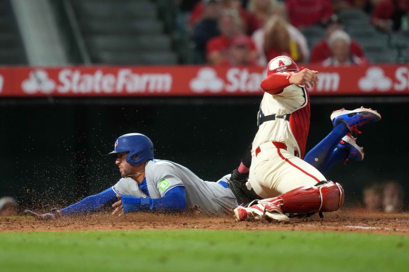 May 8, 2025; Anaheim, California, USA; Toronto Blue Jays designated hitter George Springer (4) slides into home plate to beat a throw to Los Angeles Angels catcher Logan O'Hoppe (14) to score on a throwing error in the sixth inning at Angel Stadium. Mandatory Credit: Kirby Lee-Imagn Images