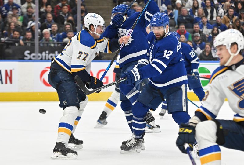 Jan 3, 2023; Toronto, Ontario, CAN; Toronto Maple Leafs forward Zach Aston-Reese (12) reaches to deflect the puck past St. Louis Blues defenseman Niko Mikkola (77) in the third period at Scotiabank Arena. Mandatory Credit: Dan Hamilton-USA TODAY Sports