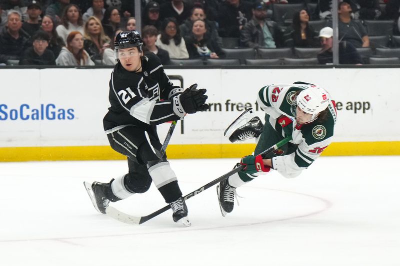 Apr 15, 2024; Los Angeles, California, USA; Minnesota Wild center Marat Khusnutdinov (22) shoots the puck against LA Kings defenseman Jordan Spence (21) in the third period at Crypto.com Arena. Mandatory Credit: Kirby Lee-USA TODAY Sports