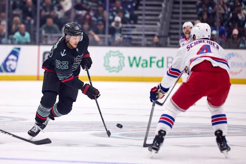 Nov 1, 2025; Seattle, Washington, USA;  Seattle Kraken defenseman Brandon Montour (62) plays the puck as New York Rangers defenseman Braden Schneider (4) defends during the first period at Climate Pledge Arena. Mandatory Credit: Blake Dahlin-Imagn Images