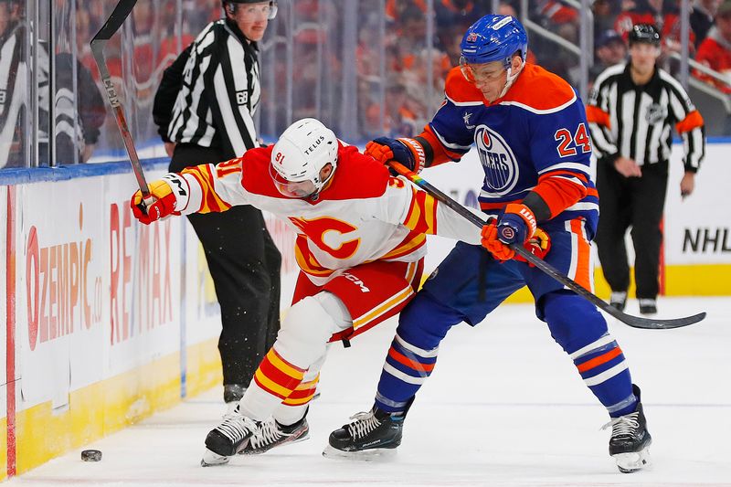 Oct 13, 2024; Edmonton, Alberta, CAN; Edmonton Oilers defensemen Travis Dermott (24) and Calgary Flames forward Name Kadri (91) battle along the boards for a loose puck during the second period at Rogers Place. Mandatory Credit: Perry Nelson-Imagn Images