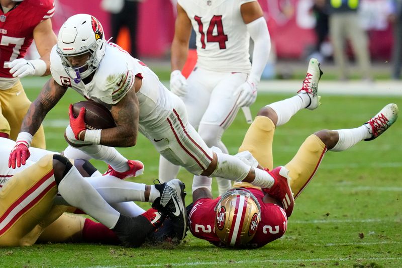 Arizona Cardinals running back James Conner, top, is tackled by San Francisco 49ers cornerback Deommodore Lenoir (2) during the first half of an NFL football game Sunday, Dec. 17, 2023, in Glendale, Ariz. (AP Photo/Ross D. Franklin)