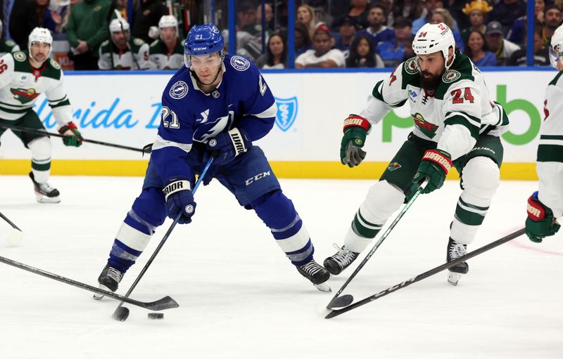 Oct 24, 2024; Tampa, Florida, USA; Tampa Bay Lightning center Brayden Point (21) skates with the puck as Minnesota Wild defenseman Zach Bogosian (24) defends during the third period at Amalie Arena. Mandatory Credit: Kim Klement Neitzel-Imagn Images