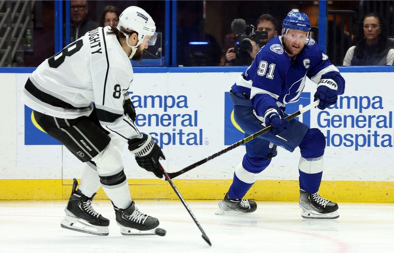 Jan 9, 2024; Tampa, Florida, USA; Tampa Bay Lightning center Steven Stamkos (91) passes the puck as Los Angeles Kings defenseman Drew Doughty (8) defends during the first period at Amalie Arena. Mandatory Credit: Kim Klement Neitzel-USA TODAY Sports