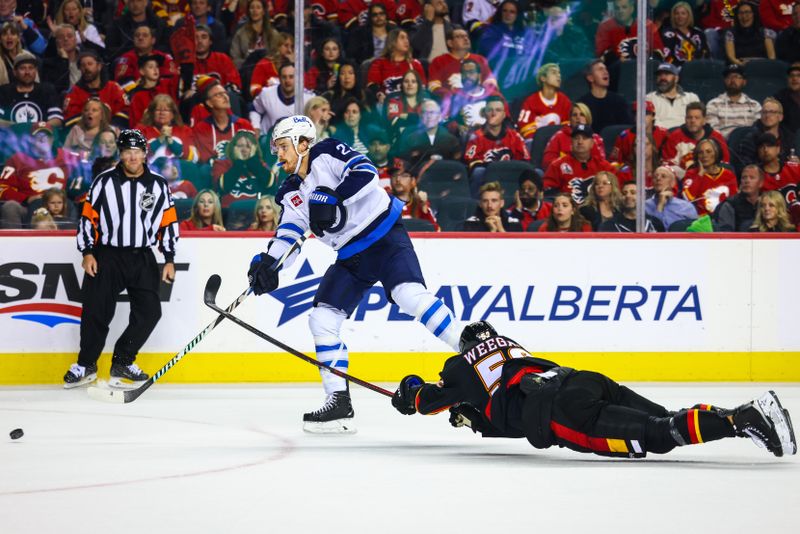 Oct 26, 2024; Calgary, Alberta, CAN; Calgary Flames defenseman MacKenzie Weegar (52) reaches for the puck as Winnipeg Jets center Mason Appleton (22) scores a goal during the third period at Scotiabank Saddledome. Mandatory Credit: Sergei Belski-Imagn Images