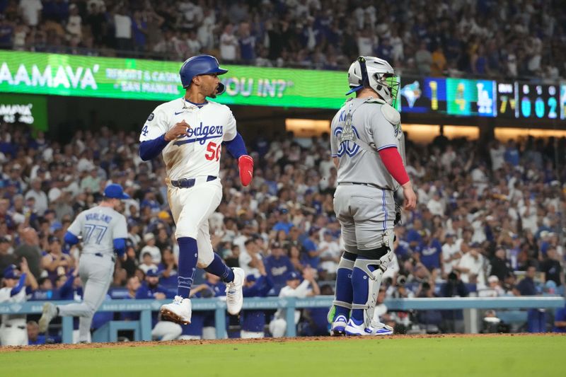 Aug 8, 2025; Los Angeles, California, USA; Los Angeles Dodgers shortstop Mookie Betts (50) scores in the seventh inning as Toronto Blue Jays catcher Alejandro Kirk (30) watches at Dodger Stadium. Mandatory Credit: Kirby Lee-Imagn Images