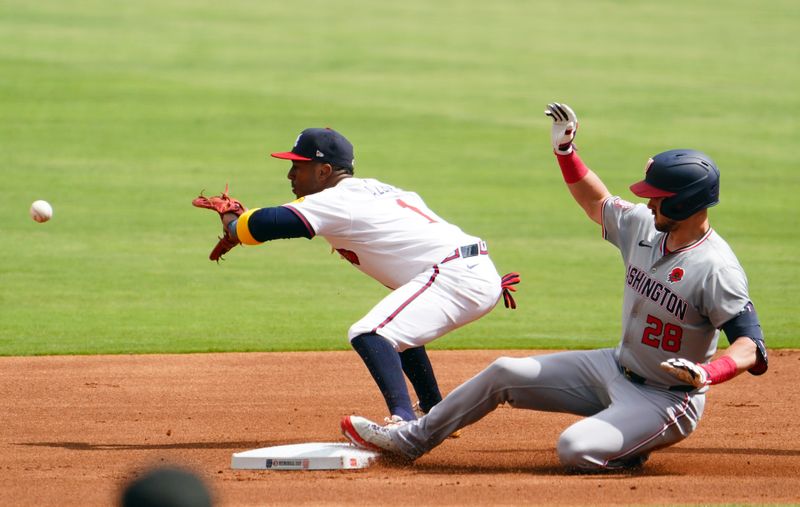 May 27, 2024; Cumberland, Georgia, USA; Washington Nationals outfielder Lane Thomas (28) slides into to second base safely under Atlanta Braves second baseman Ozzie Albies (1) during the first inning at Truist Park. Mandatory Credit: John David Mercer-USA TODAY Sports