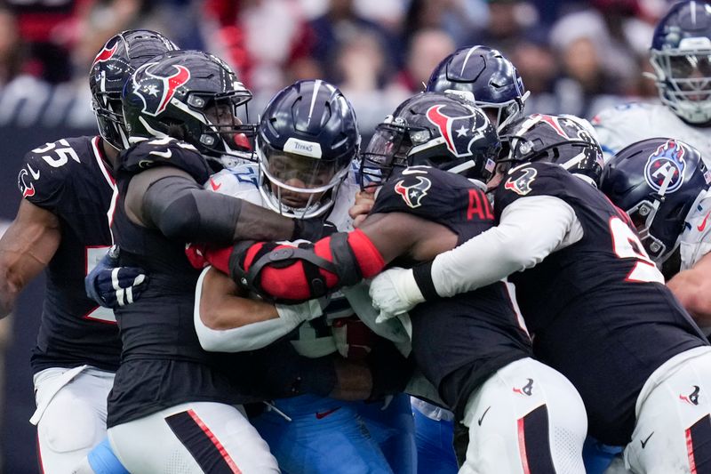 Tennessee Titans running back Tony Pollard, center, is tackled the Houston Texans defense during the second half an NFL football game Sunday, Nov. 24, 2024, in Houston. (AP Photo/Eric Christian Smith)