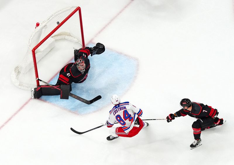 Nov 27, 2024; Raleigh, North Carolina, USA;  New York Rangers center Adam Edstrom (84) scores a goal past Carolina Hurricanes goaltender Spencer Martin (41) and  defenseman Dmitry Orlov (7) during the second period at Lenovo Center. Mandatory Credit: James Guillory-Imagn Images