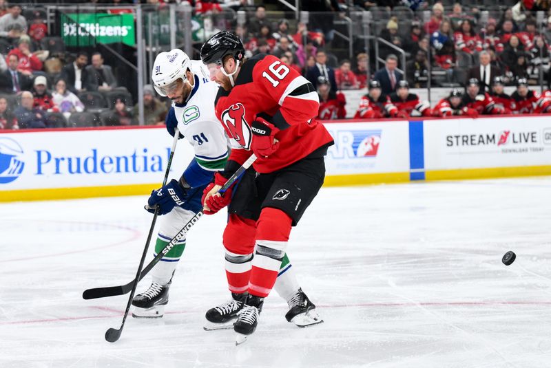 Dec 14, 2025; Newark, New Jersey, USA; Vancouver Canucks left wing Evander Kane (91) passes the puck while defended by New Jersey Devils right wing Connor Brown (16) during the first period at Prudential Center. Mandatory Credit: John Jones-Imagn Images