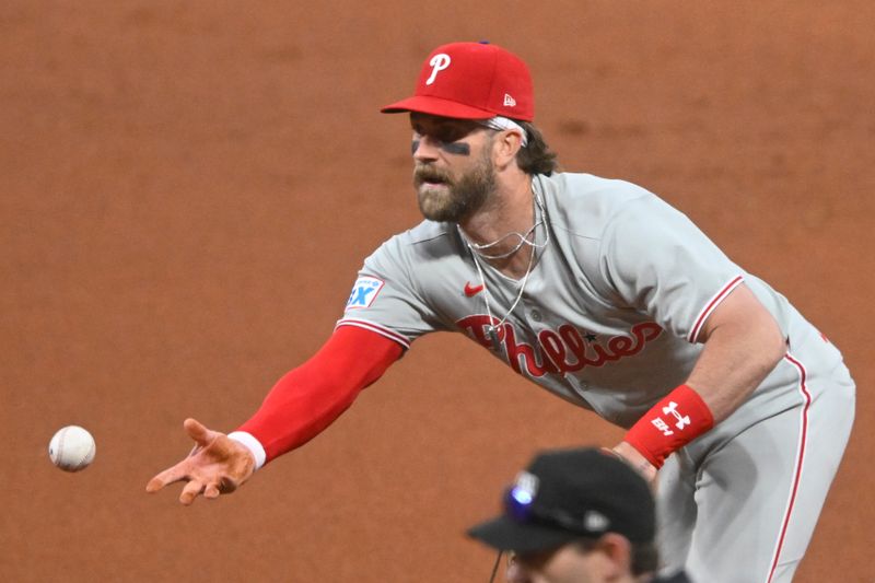May 9, 2025; Cleveland, Ohio, USA; Philadelphia Phillies first baseman Bryce Harper (3) tosses the ball to first base in the fifth inning against the Cleveland Guardians at Progressive Field. Mandatory Credit: David Richard-Imagn Images