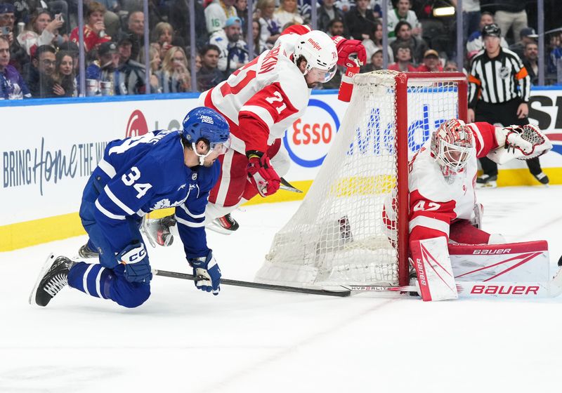 Apr 13, 2024; Toronto, Ontario, CAN; Toronto Maple Leafs center Auston Matthews (34) battles for the puck beside the net with Detroit Red Wings center Dylan Larkin (71) during the third period at Scotiabank Arena. Mandatory Credit: Nick Turchiaro-USA TODAY Sports