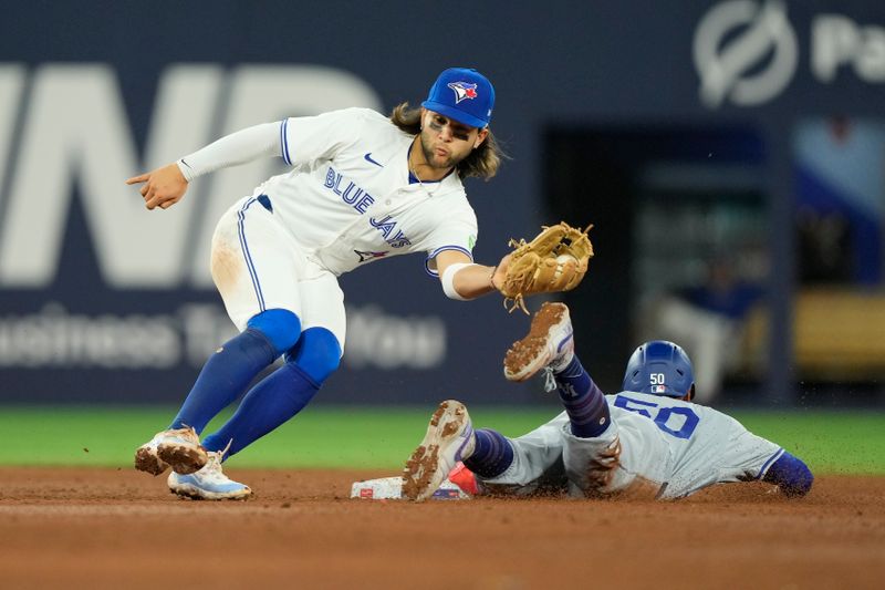 Apr 27, 2024; Toronto, Ontario, CAN; Los Angeles Dodgers second baseman Mookie Betts (50) beats the tag from Toronto Blue Jays shortstop Bo Bichette (11) to steal second base during the ninth inning at Rogers Centre. Mandatory Credit: John E. Sokolowski-USA TODAY Sports