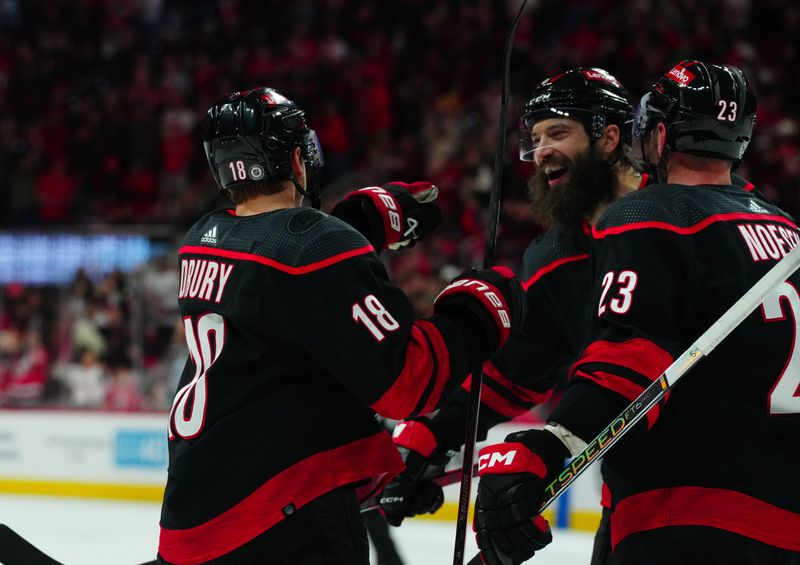 Dec 2, 2023; Raleigh, North Carolina, USA; Carolina Hurricanes center Jack Drury (18) is congratulated by Carolina Hurricanes defenseman Brent Burns (8) and Carolina Hurricanes right wing Stefan Noesen (23) after his goal against the Buffalo Sabres during the first period at PNC Arena. Mandatory Credit: James Guillory-USA TODAY Sports