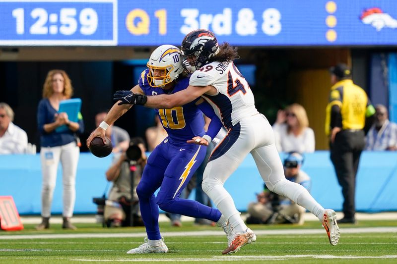 Denver Broncos linebacker Alex Singleton (49) sacks Los Angeles Chargers quarterback Justin Herbert (10) during the first half of an NFL football game Sunday, Dec. 10, 2023, in Inglewood, Calif. (AP Photo/Ryan Sun)