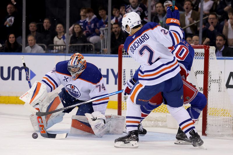 Oct 14, 2025; New York, New York, USA; Edmonton Oilers goaltender Stuart Skinner (74) makes a save against New York Rangers left wing Will Cuylle (50) in front of Oilers defenseman Evan Bouchard (2) during the first period at Madison Square Garden. Mandatory Credit: Brad Penner-Imagn Images
