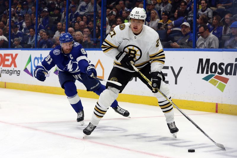 Nov 20, 2023; Tampa, Florida, USA; Boston Bruins defenseman Hampus Lindholm (27) skates with the puck as Tampa Bay Lightning center Steven Stamkos (91) defends during the first period at Amalie Arena. Mandatory Credit: Kim Klement Neitzel-USA TODAY Sports