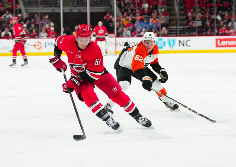 Mar 21, 2024; Raleigh, North Carolina, USA; Carolina Hurricanes left wing Jake Guentzel (59) skates with the puck past Philadelphia Flyers right wing Olle Lycksell (62) during the first period at PNC Arena. Mandatory Credit: James Guillory-USA TODAY Sports