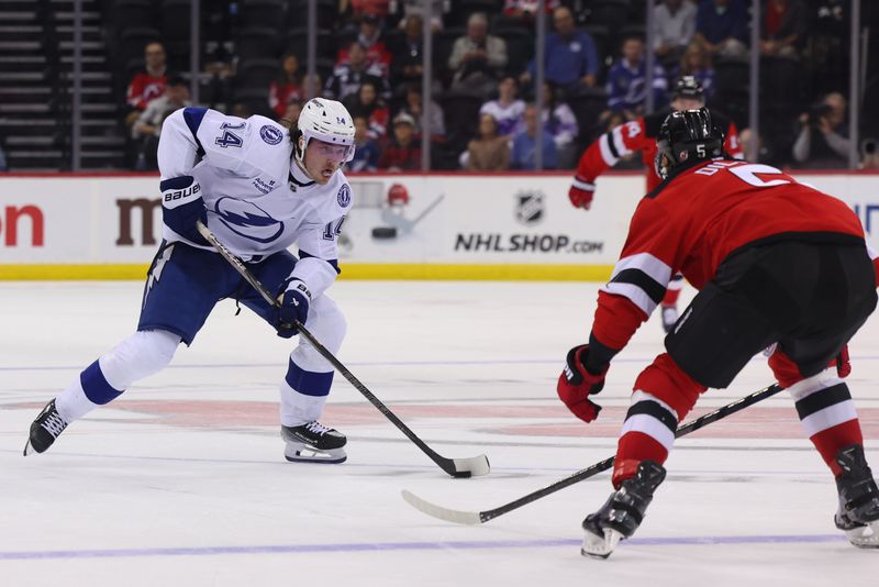 Oct 22, 2024; Newark, New Jersey, USA; Tampa Bay Lightning center Conor Geekie (14) skates with the puck while defended by New Jersey Devils defenseman Brenden Dillon (5) during the third period at Prudential Center. Mandatory Credit: Ed Mulholland-Imagn Images