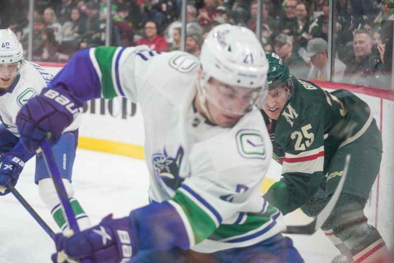 Feb 19, 2024; Saint Paul, Minnesota, USA; Minnesota Wild defenseman Jonas Brodin (25) and Vancouver Canucks left wing Nils Hoglander (21) make a play along the boards in the third period at Xcel Energy Center. Mandatory Credit: Matt Blewett-USA TODAY Sports