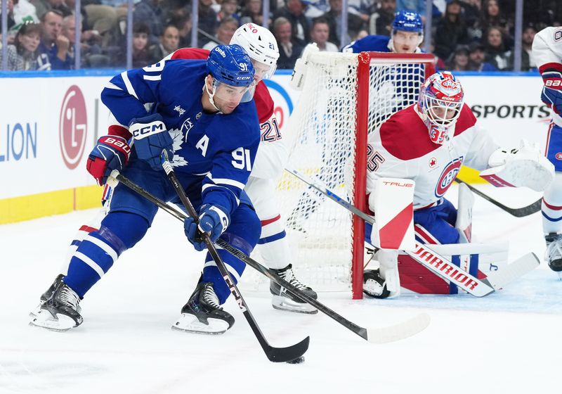 Oct 8, 2025; Toronto, Ontario, CAN; Toronto Maple Leafs center John Tavares (91)battles for the puck with Montreal Canadiens defenseman Kaiden Guhle (21) during the first period at Scotiabank Arena. Mandatory Credit: Nick Turchiaro-Imagn Images