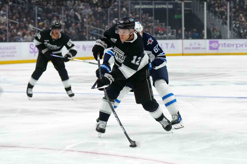 Nov 27, 2024; Los Angeles, California, USA; LA Kings left wing Trevor Moore (12) shoots the puck against the Winnipeg Jets in the second period at Crypto.com Arena. Mandatory Credit: Kirby Lee-Imagn Images