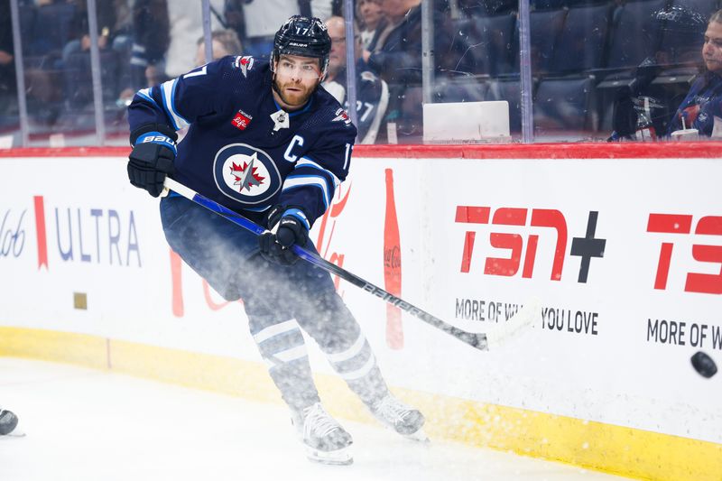 Apr 16, 2024; Winnipeg, Manitoba, CAN;  Winnipeg Jets forward Adam Lowry (17) clears the puck against the Seattle Kraken during the first period at Canada Life Centre. Mandatory Credit: Terrence Lee-USA TODAY Sports