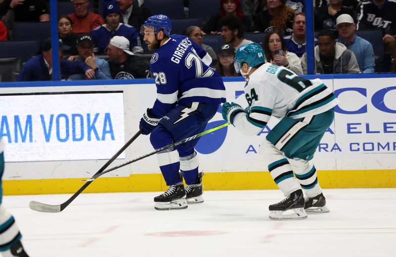 Dec 5, 2024; Tampa, Florida, USA; Tampa Bay Lightning center Zemgus Girgensons (28) skates as San Jose Sharks center Mikael Granlund (64) defends during the third period at Amalie Arena. Mandatory Credit: Kim Klement Neitzel-Imagn Images