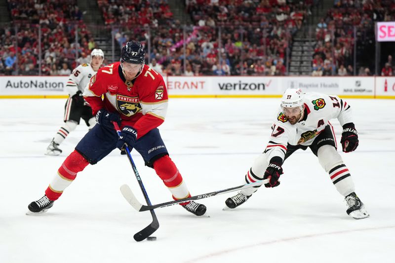 Nov 12, 2023; Sunrise, Florida, USA; Chicago Blackhawks left wing Nick Foligno (17) reaches for the puck on Florida Panthers defenseman Niko Mikkola (77) during the first period at Amerant Bank Arena. Mandatory Credit: Jasen Vinlove-USA TODAY Sports